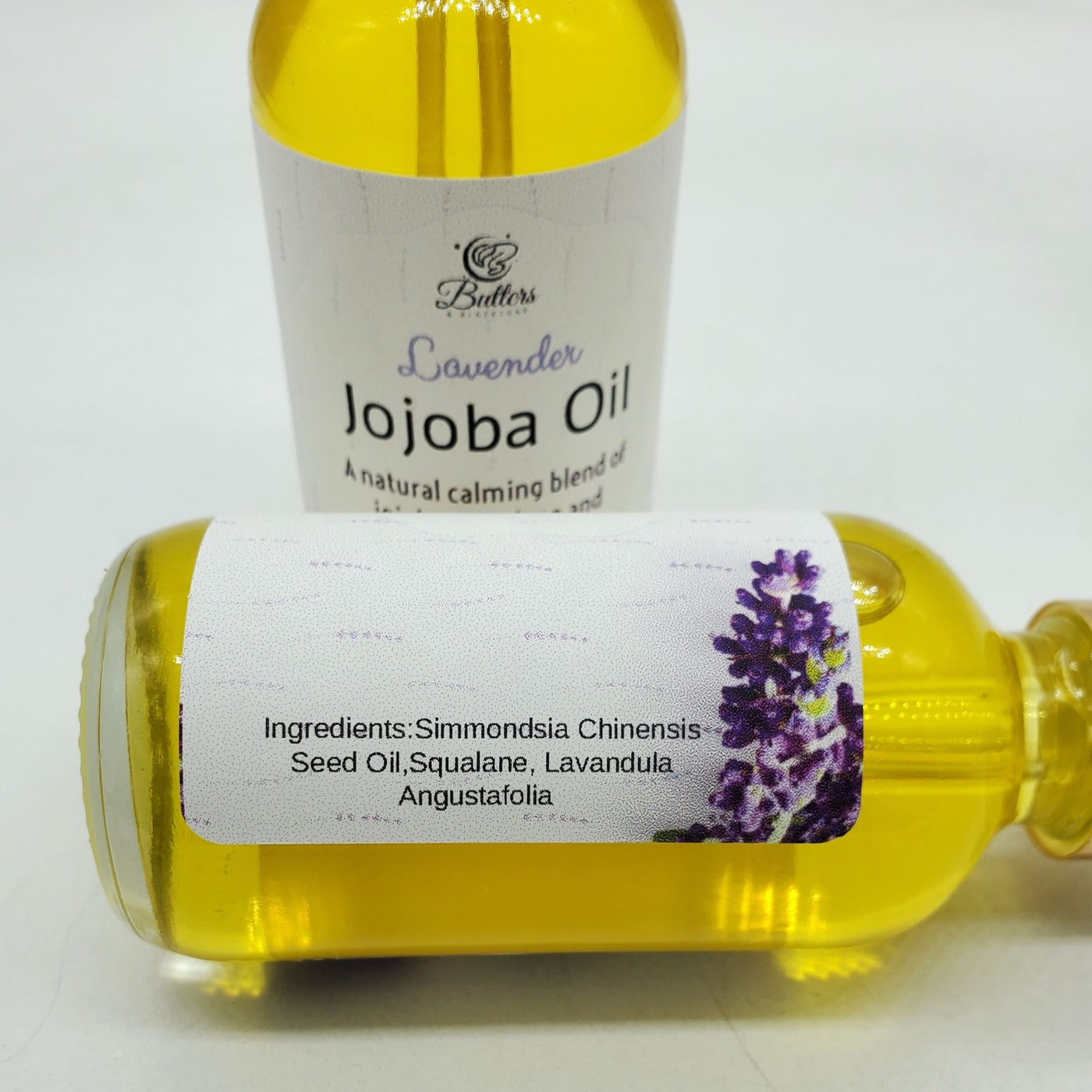 two bottles of lavender jojoba oil. one is standing upright the other is layin on its side showing the list of ingredients