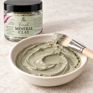 French green clay mixed into a paste in a ceramic bowl with a facial brush and product jar.