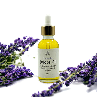 bottle of lavender jojoba oil in between two sprigs of lavender flower. 