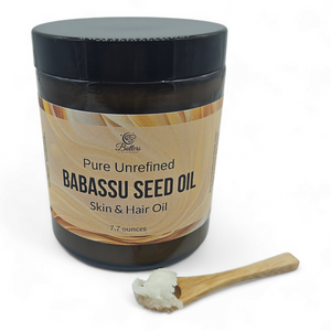 A jar of babassu oil with a spoonful of babassu oil sitting in front