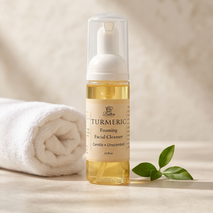 bottle of facial cleanser next to towels and natural green leaf