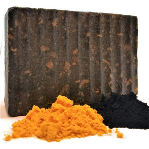 bar of african black soap with a pile of turmeric and charcoal powder